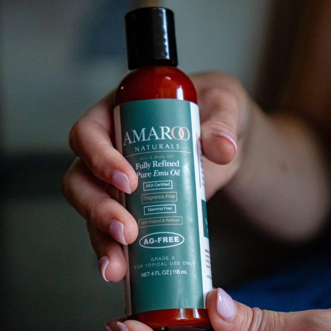 A hand holding a bottle of Amaroo Naturals Fully Refined Pure Emu Oil with the label facing forward