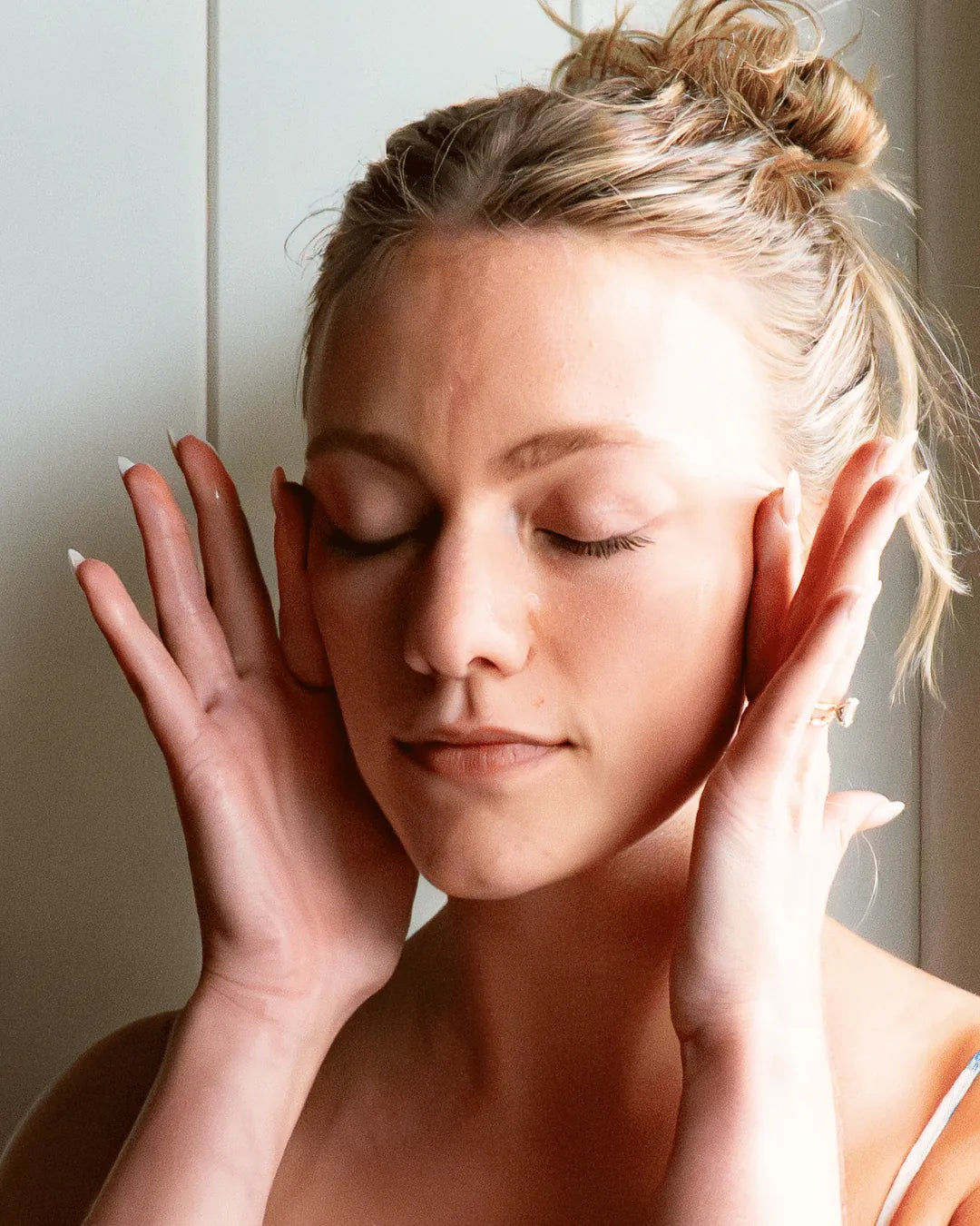 A woman rubs Amaroo Naturals emu oil into her face and cheekbones