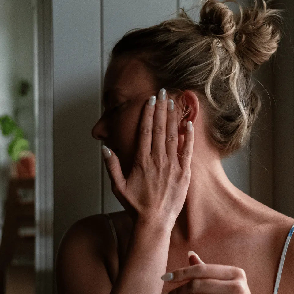 A woman with blonde hair in a messy bun rubbing Amaroo Naturals emu oil into her hair